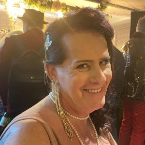 Marteene smiling at an event, wearing pearl jewelry and a sparkly butterfly hair clip.