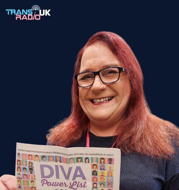 Lucy Clark, a smiling trans woman with long red hair and glasses, holding a copy of the DIVA Power List newspaper. She stands against a navy blue background featuring the Trans Radio UK logo in the top left.