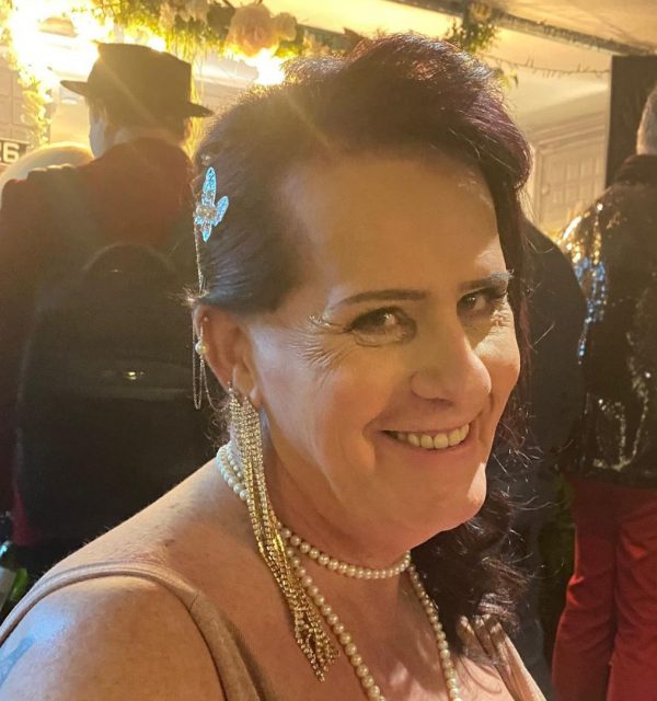 Marteene smiling at an event, wearing pearl jewelry and a sparkly butterfly hair clip.